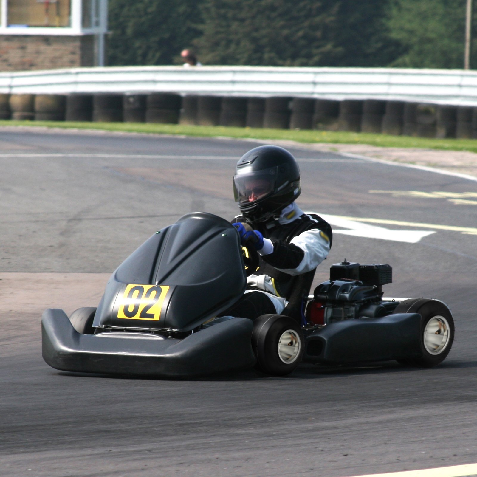 Kart de carreras n.° 02 en la pista con neumáticos de kart VEVOR. Piloto con equipo negro conduciendo por una curva.