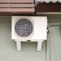Unidad de aire acondicionado exterior montada en un soporte de aire acondicionado VEVOR debajo del toldo de una casa.