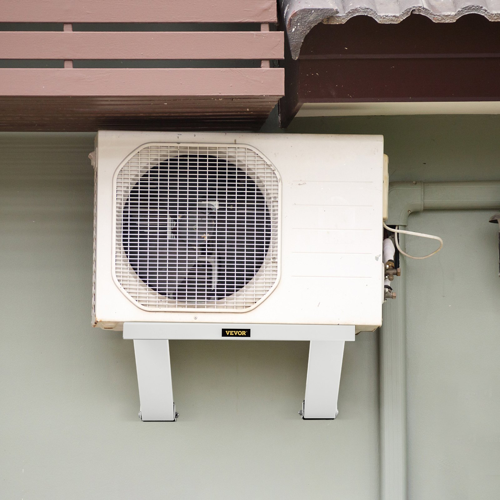 Unidad de aire acondicionado exterior montada en un soporte de aire acondicionado VEVOR debajo del toldo de una casa.