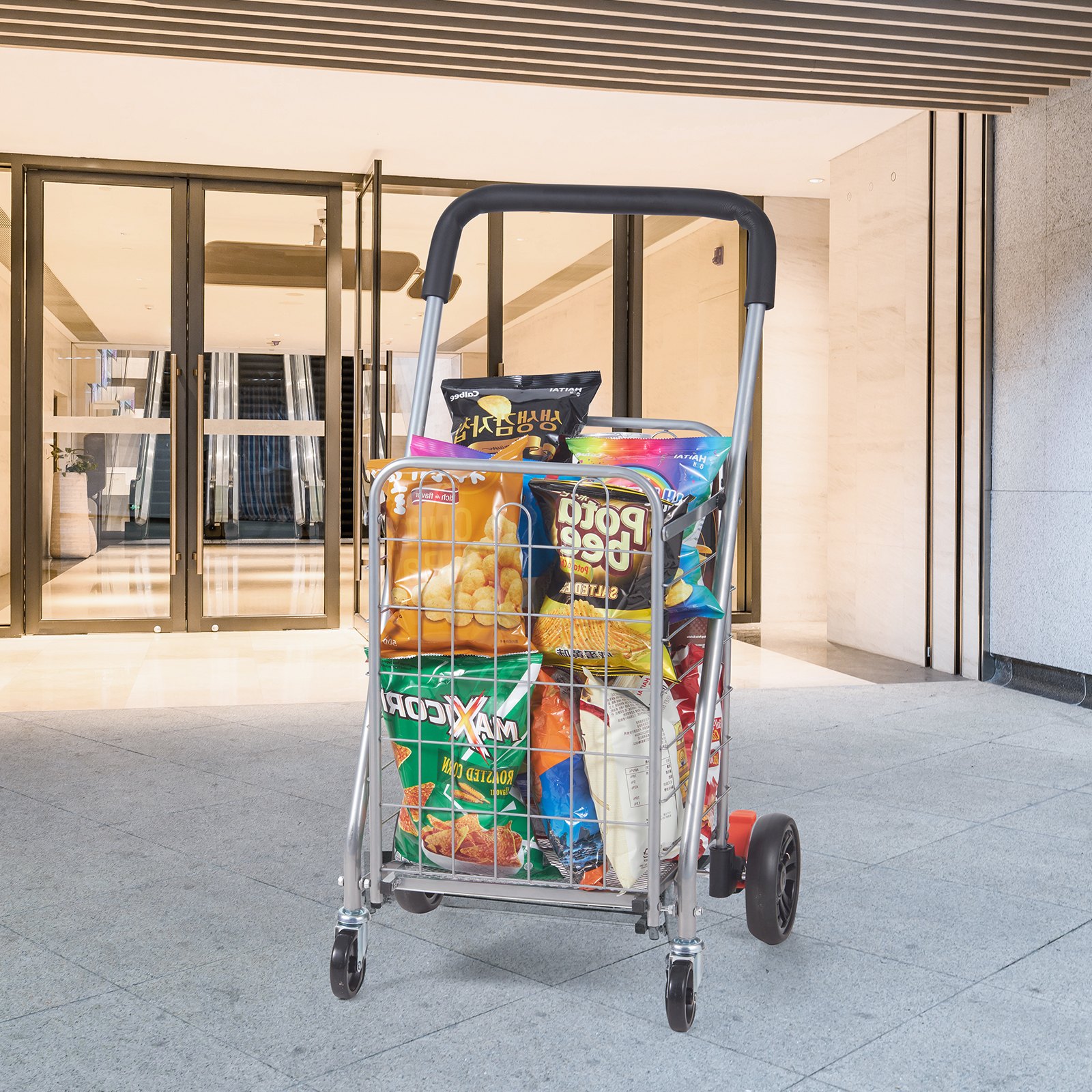 Carrito de compras plegable VEVOR cargado con comestibles frente a la entrada de un edificio moderno.