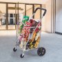 Carrito de compras plegable VEVOR lleno de comestibles afuera de la entrada de un edificio moderno.
