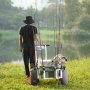 Hombre tirando de un carrito de pesca de playa VEVOR cargado con cañas y aparejos junto a un pintoresco lago.