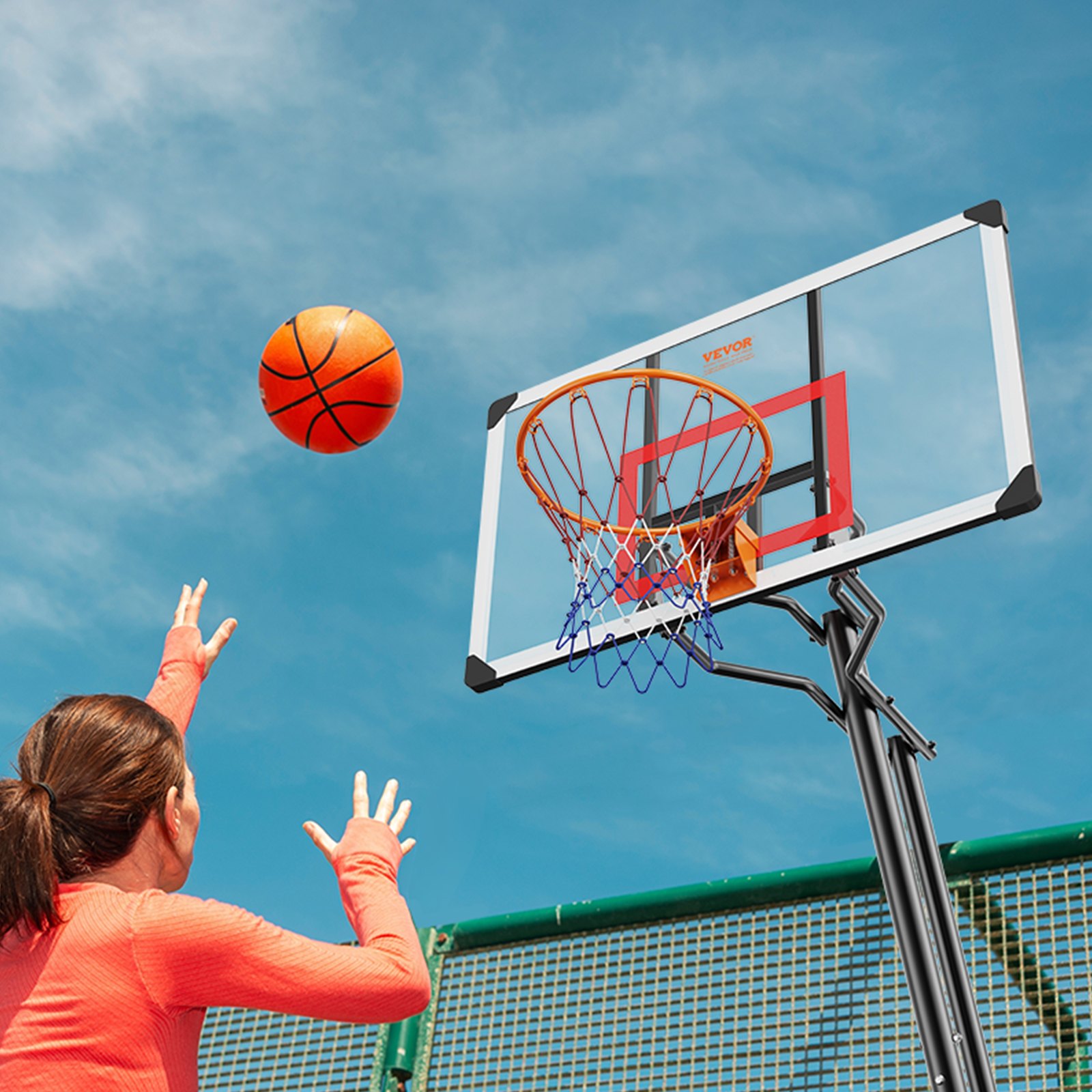 Persona disparando baloncesto en el aro de baloncesto VEVOR bajo un cielo despejado.