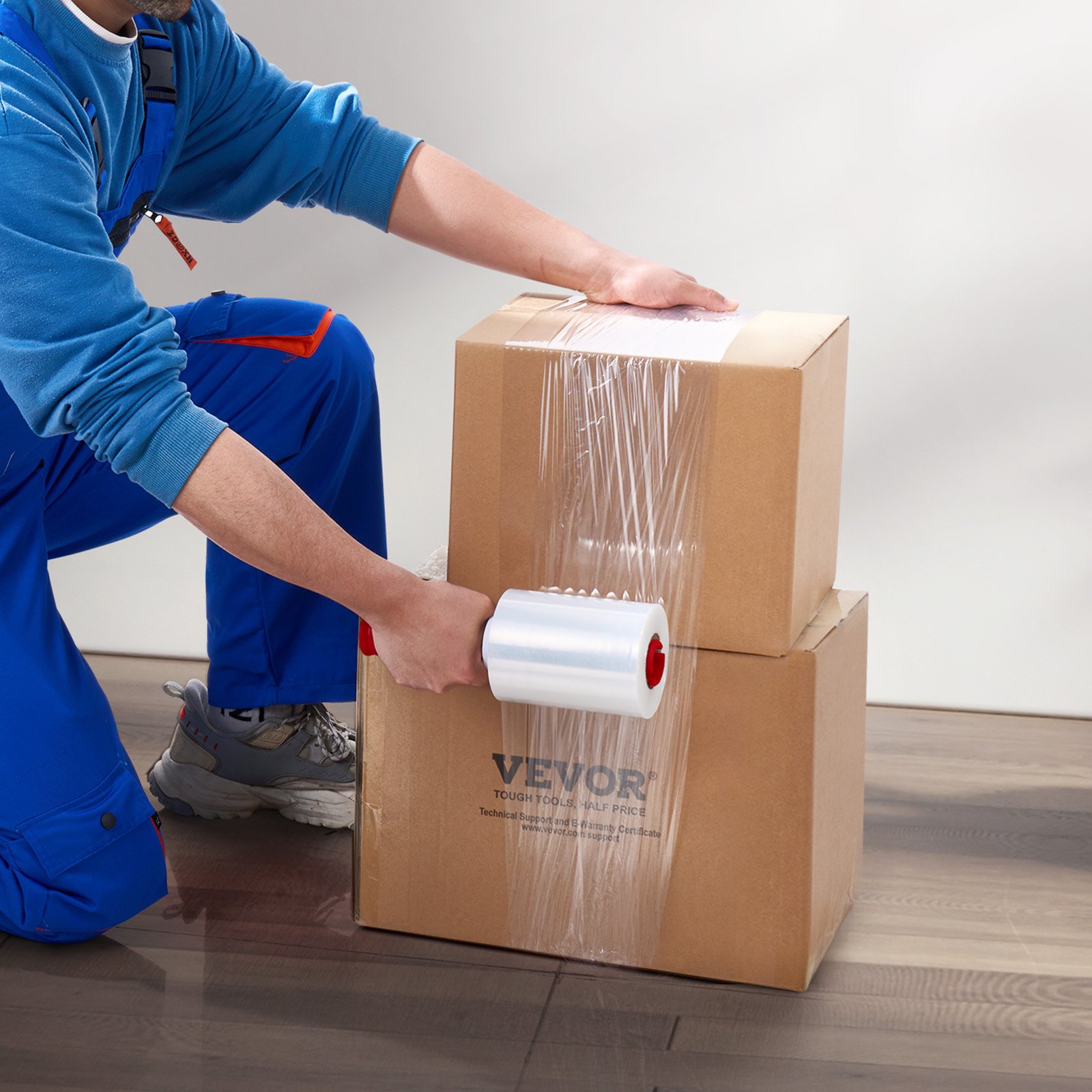 Persona envolviendo cajas de cartón con film estirable VEVOR sobre un suelo de madera.