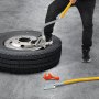 Persona que utiliza la herramienta de montaje y desmontaje de neumáticos VEVOR en un neumático con una herramienta adicional en el suelo.