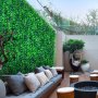 Zona de estar al aire libre con paneles de boj VEVOR, muebles modernos y exuberante vegetación.
