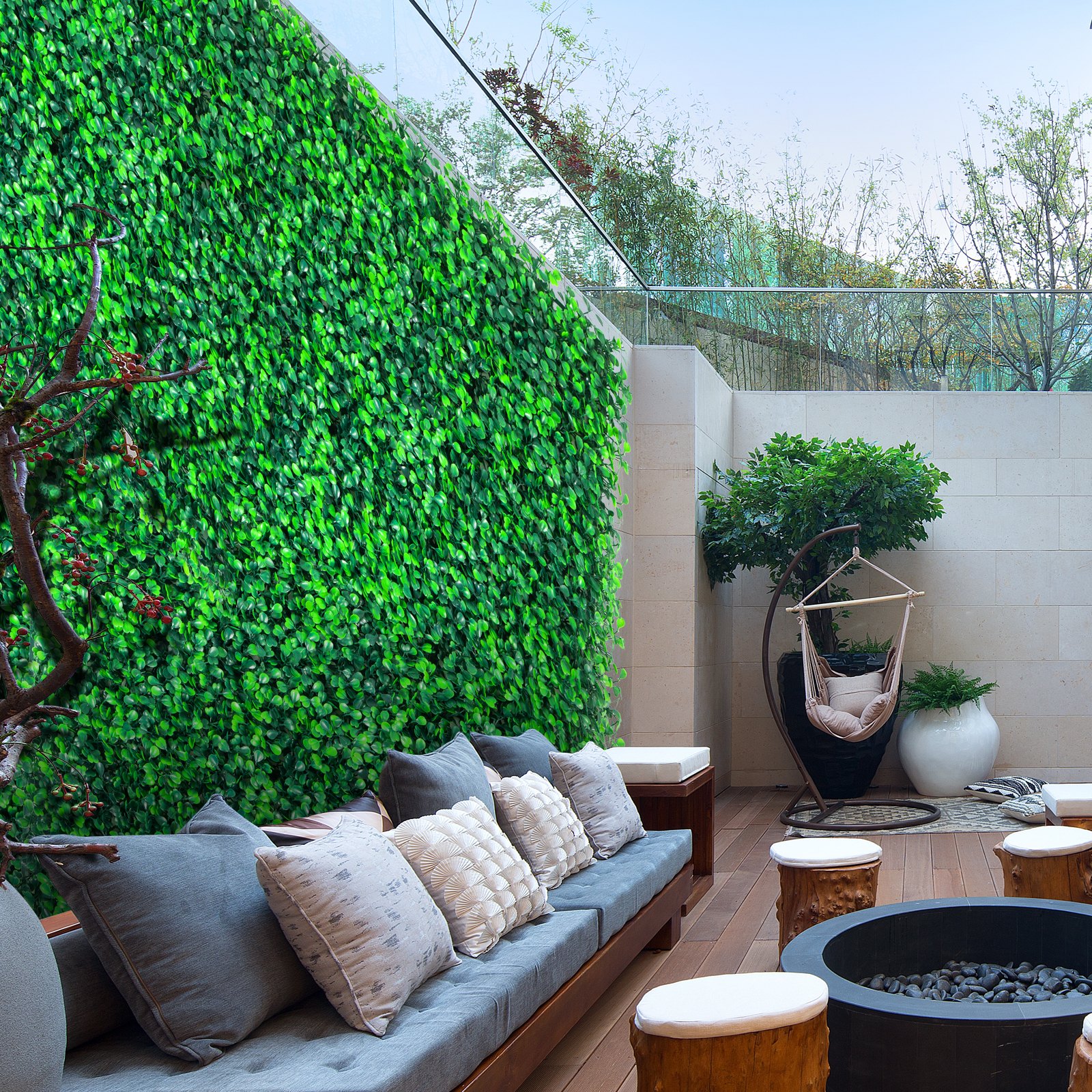 Zona de estar al aire libre con paneles de boj VEVOR, muebles modernos y exuberante vegetación.