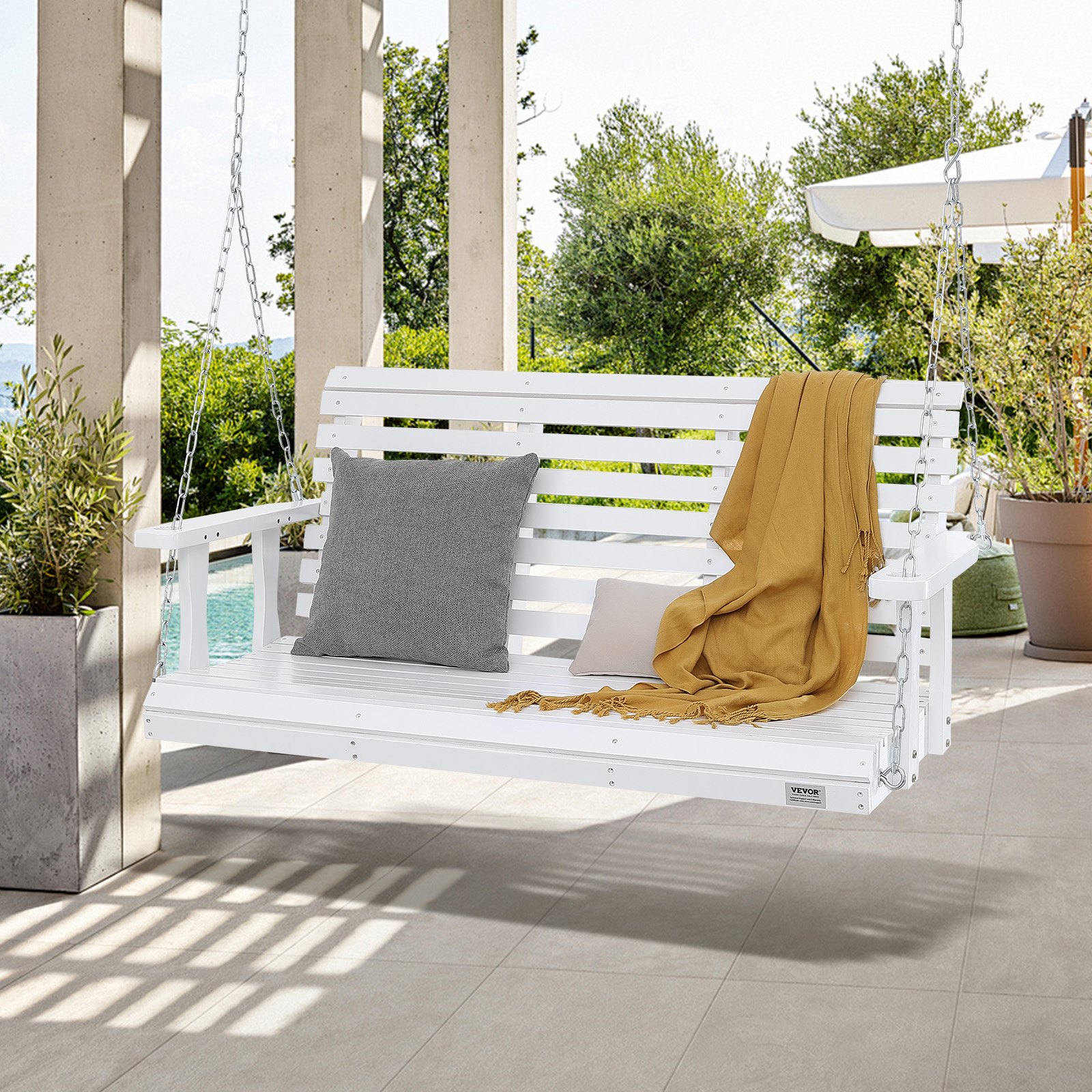 Columpio de porche de madera VEVOR en color blanco con cojín gris y manta mostaza, colgado al aire libre cerca de una piscina.