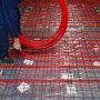Instalación de tubería pex VEVOR en un sistema de calefacción por suelo radiante con tubería roja y base.