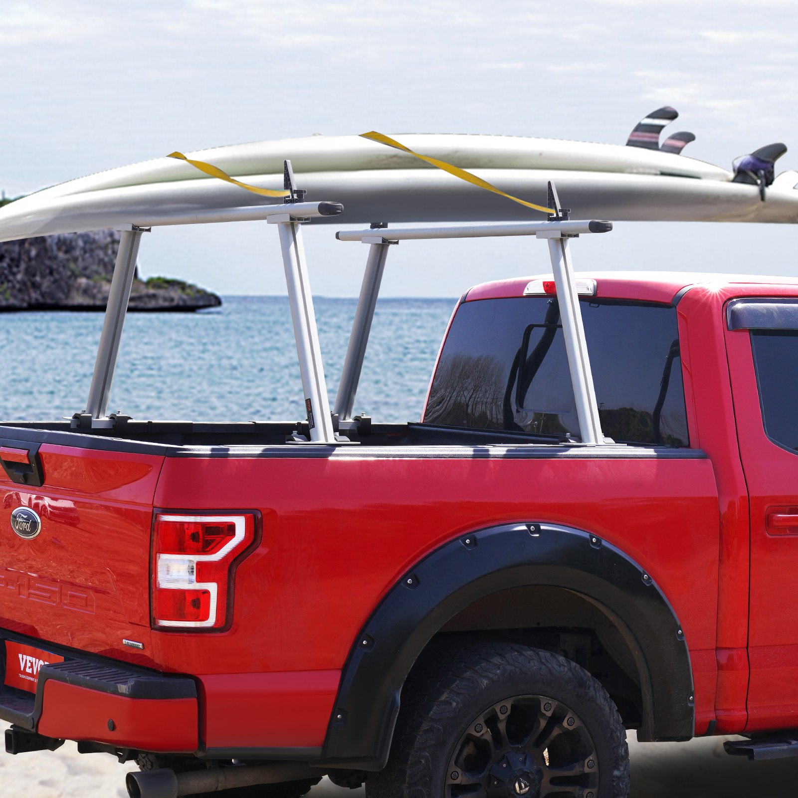 Camión rojo con portaequipajes VEVOR que transporta tablas de surf en la playa.