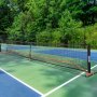 Red de pickleball VEVOR ubicada en una cancha al aire libre rodeada de frondosos árboles verdes.
