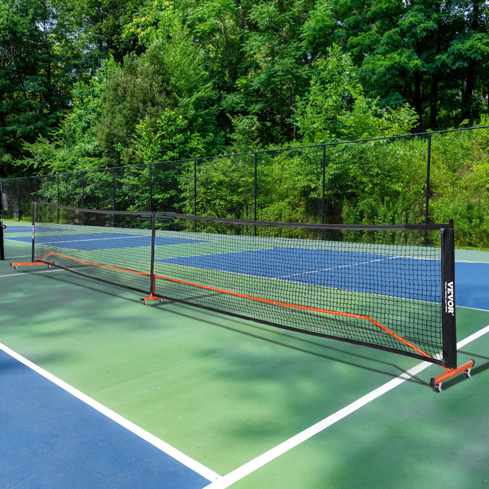 Red de pickleball VEVOR ubicada en una cancha al aire libre rodeada de frondosos árboles verdes.