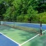 Red de pickleball VEVOR ubicada en una cancha al aire libre con frondosos árboles verdes de fondo.
