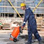 Trabajador con equipo de protección que utiliza una máquina pulidora de arena VEVOR en un sitio de construcción con andamios al fondo.