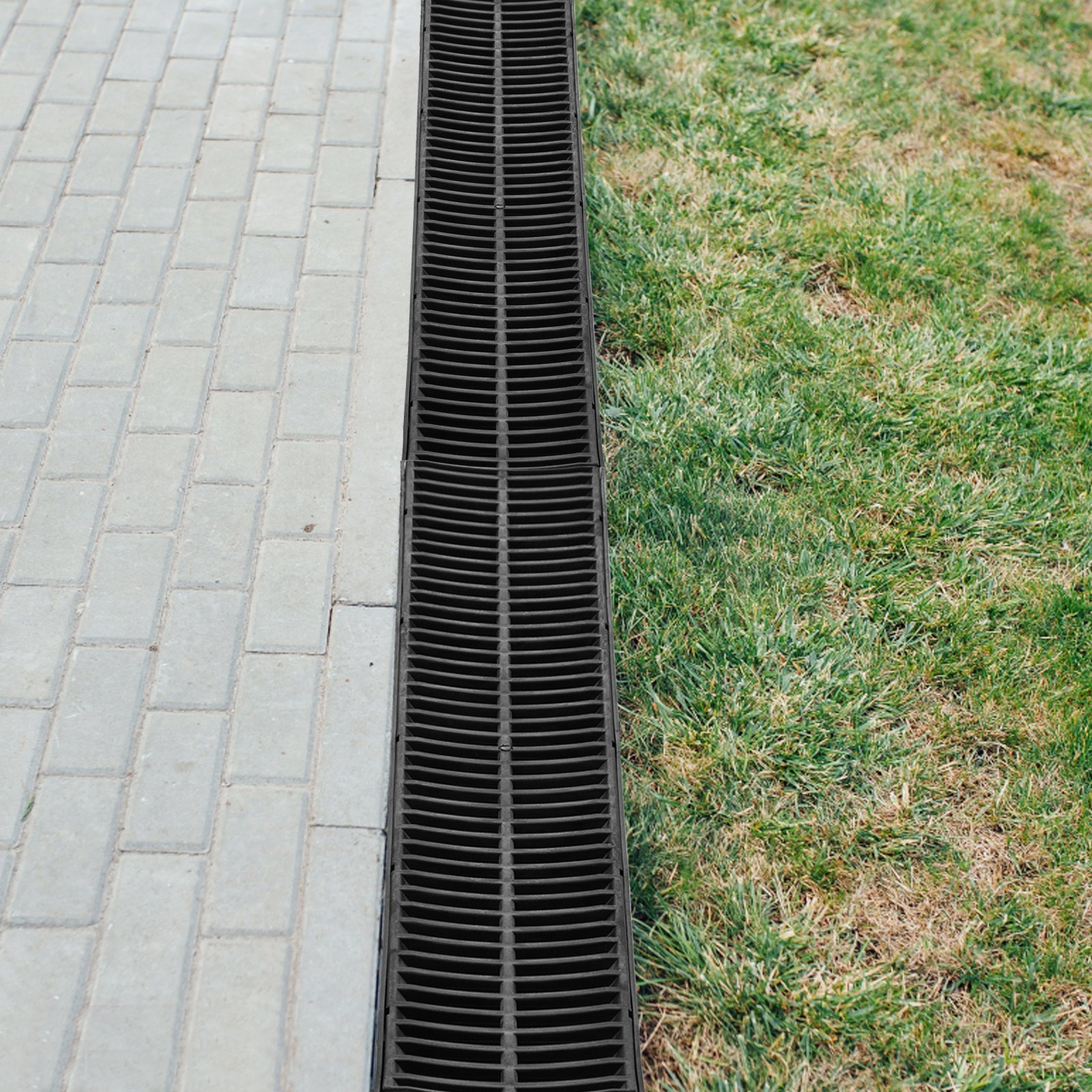 Sistema de drenaje de zanja VEVOR junto a un camino pavimentado y césped verde.