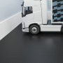 Camión blanco sobre un elegante piso de baldosas de garaje VEVOR de color negro junto a una superficie estampada en azul y negro.