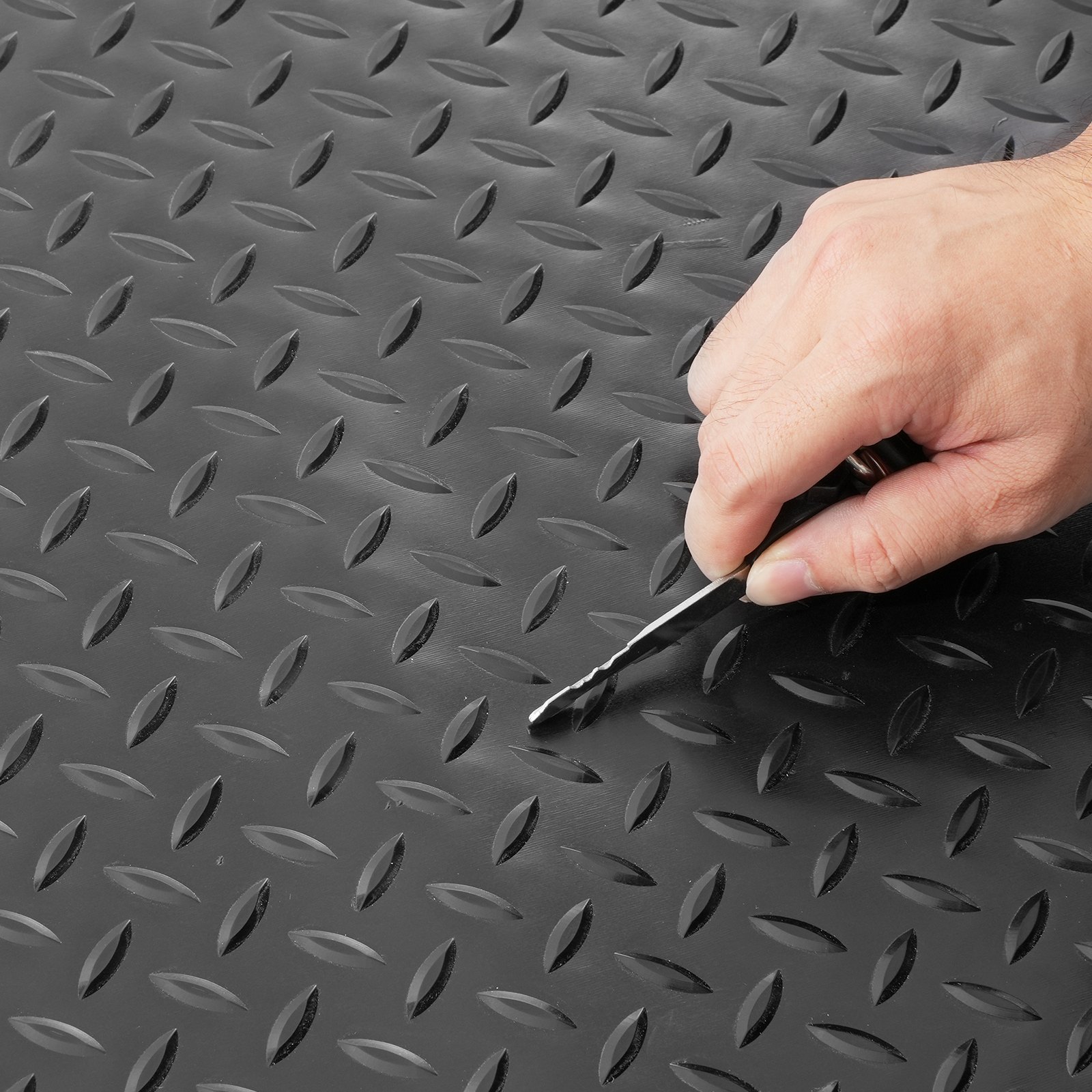 Mano que señala las alfombrillas de garaje negras VEVOR con textura de placa de diamante.
