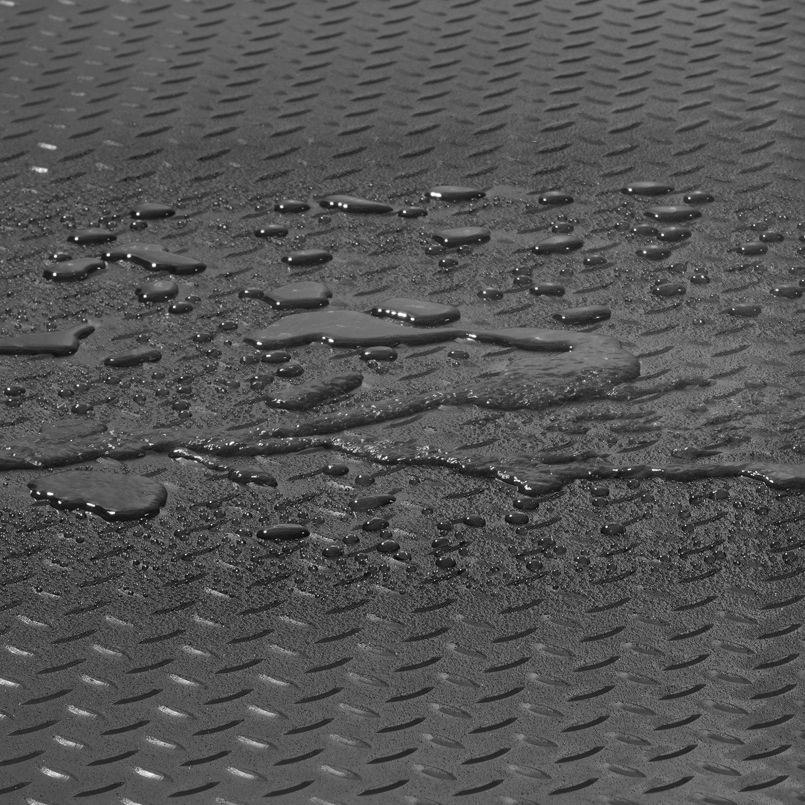 Gotas de agua sobre alfombrillas de garaje texturizadas VEVOR, que muestran una superficie antideslizante.