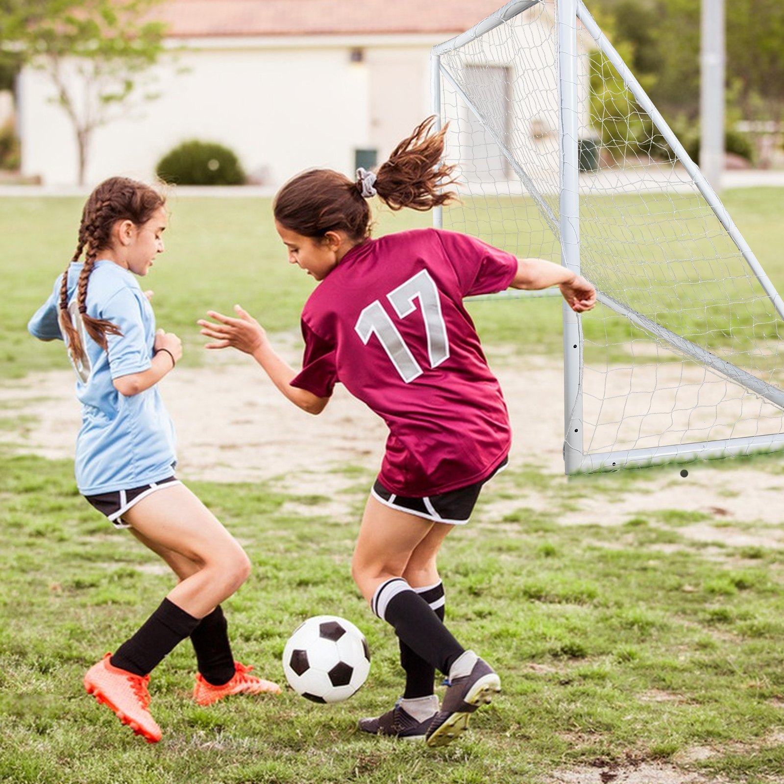Niñas jugando al fútbol cerca de una portería de fútbol portátil VEVOR en un campo de césped.