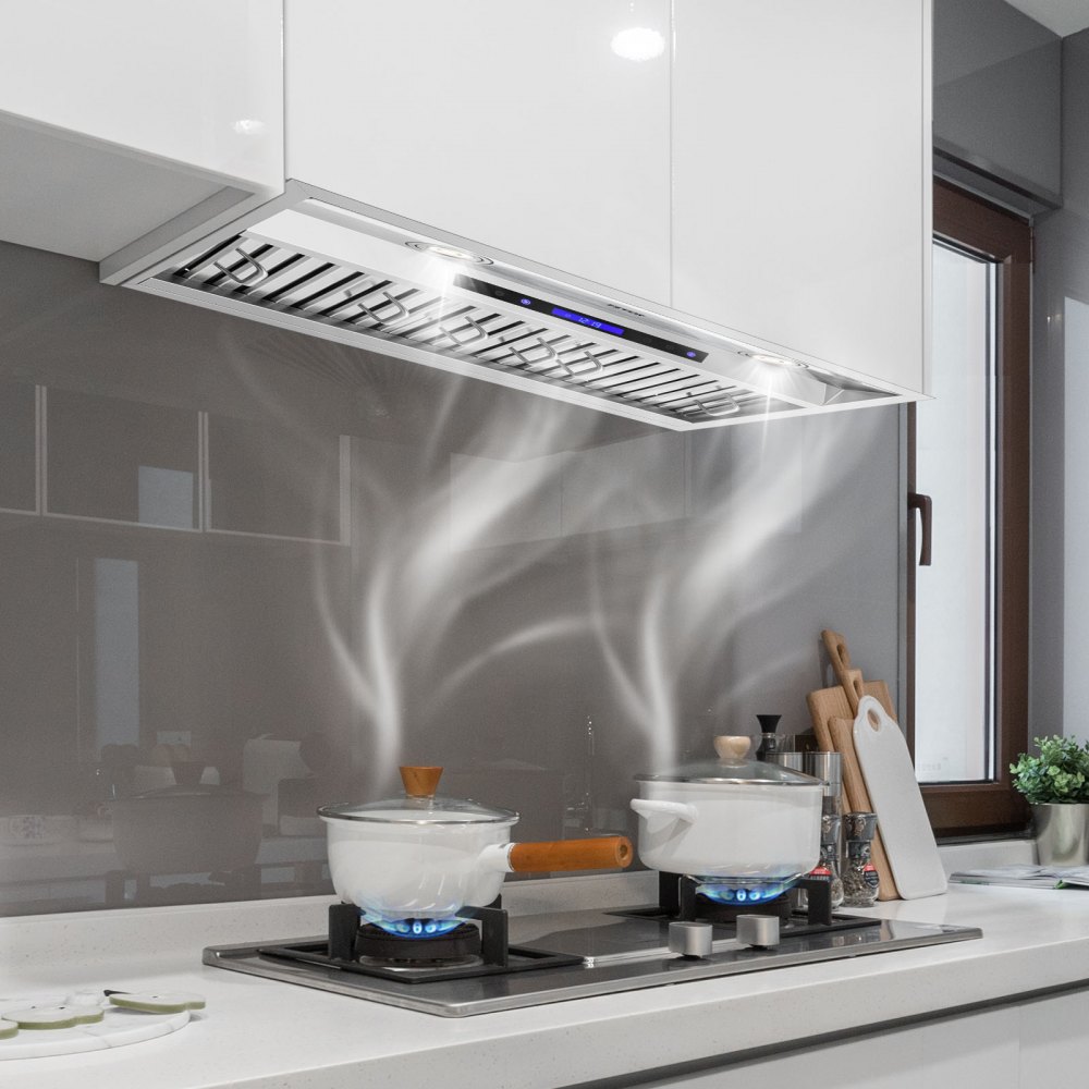 Cocina moderna con campana extractora insertable VEVOR sobre la estufa, que captura el vapor de las ollas hirviendo.