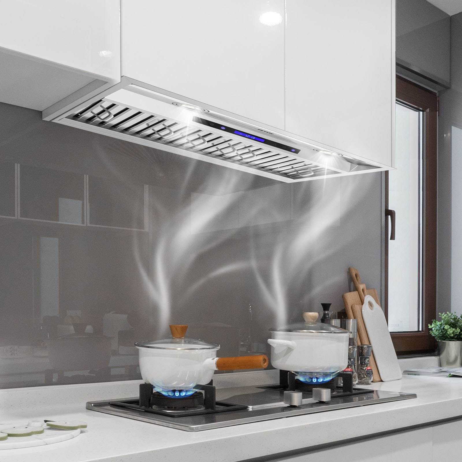 Cocina moderna con campana extractora insertable VEVOR sobre la estufa, que captura el vapor de las ollas hirviendo.