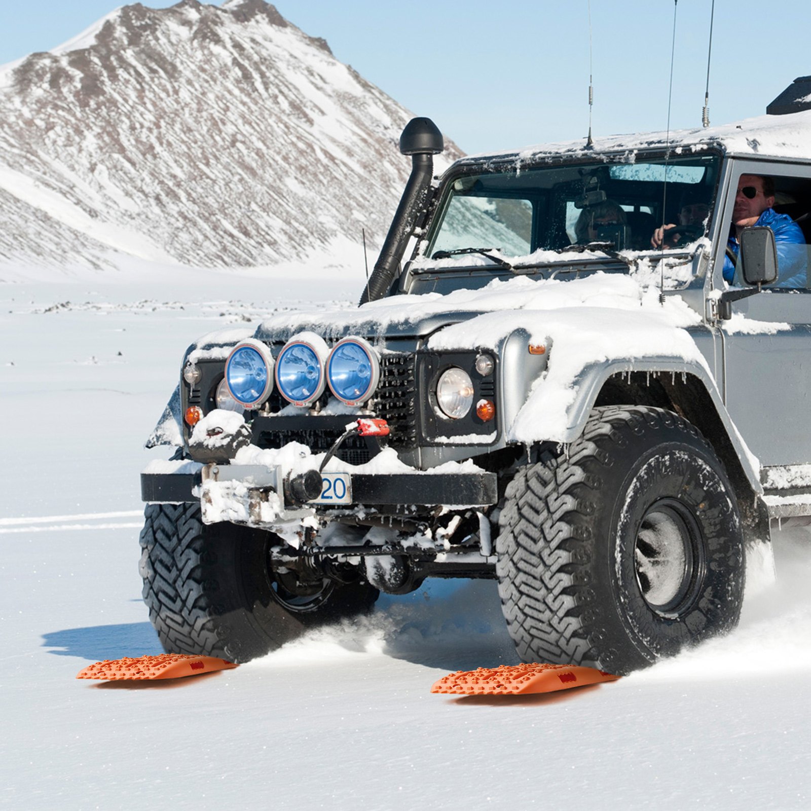 SUV usando placas de tracción VEVOR en terreno nevado con fondo montañoso.