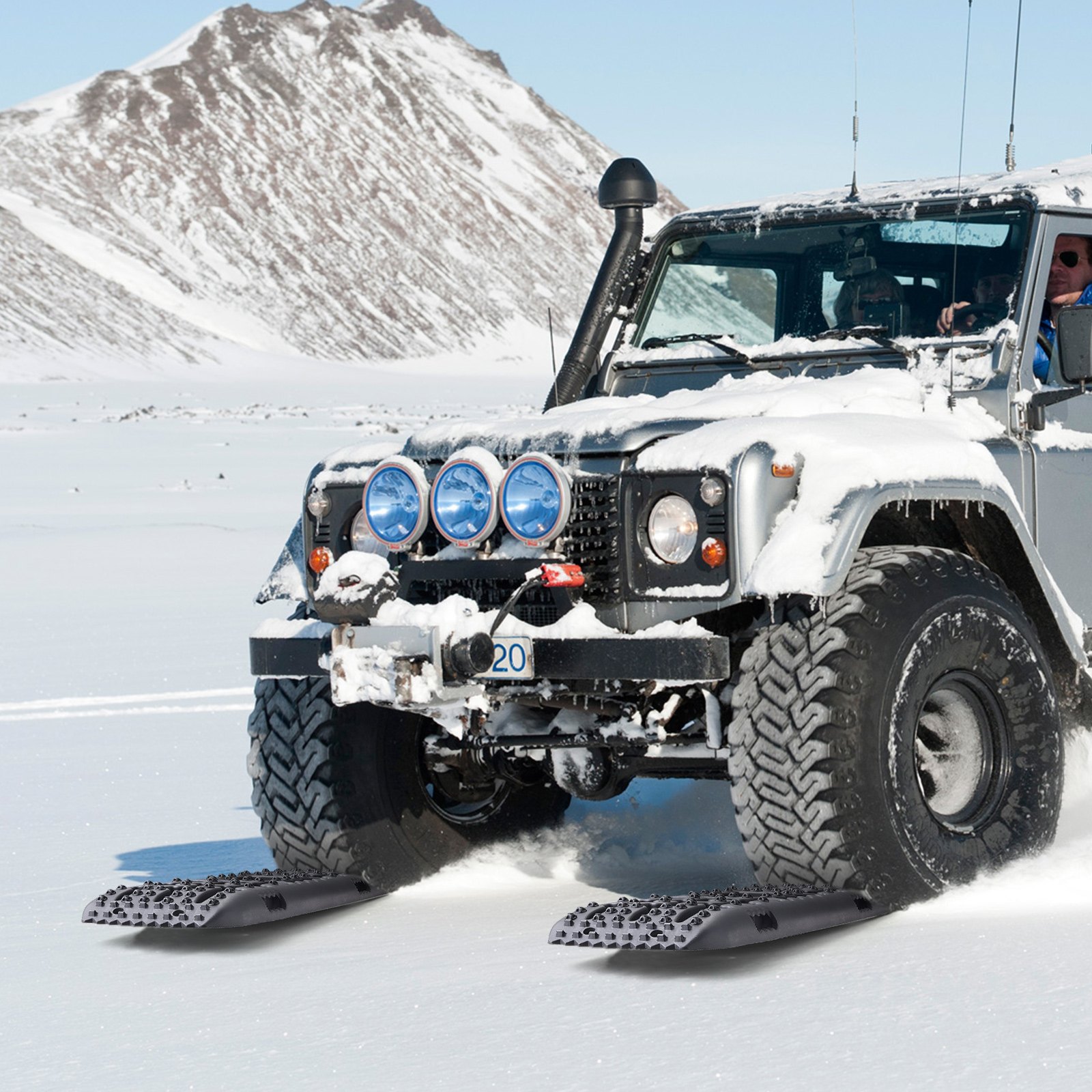 SUV todoterreno sobre nieve usando placas de tracción VEVOR con una montaña cubierta de nieve al fondo.