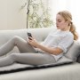 Mujer relajándose en un cojín de masaje de cuerpo completo VEVOR mientras usa un teléfono inteligente en un sofá.