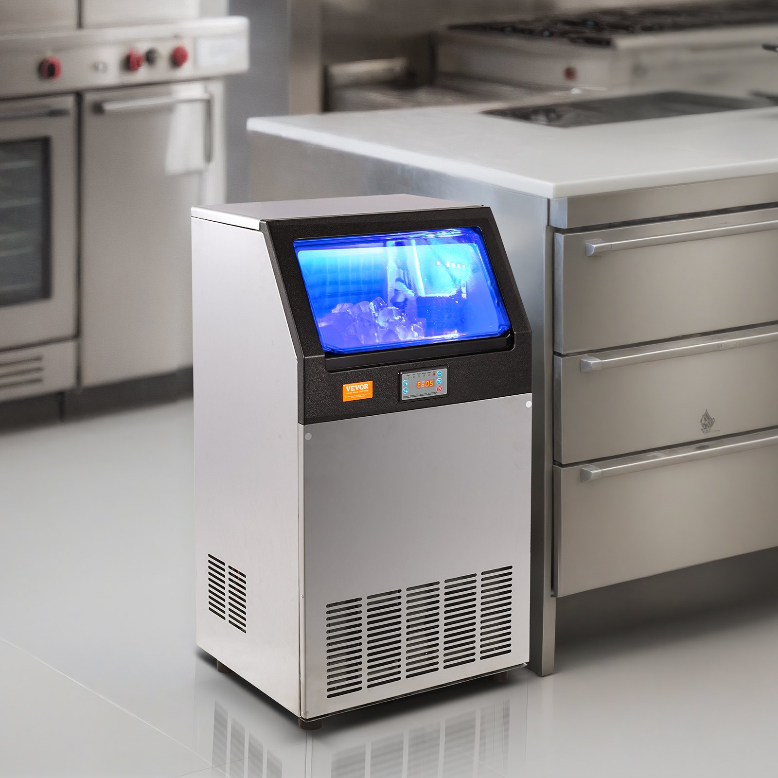 Máquina de hielo comercial VEVOR en una cocina profesional, con depósito de hielo iluminado en azul y panel de control.