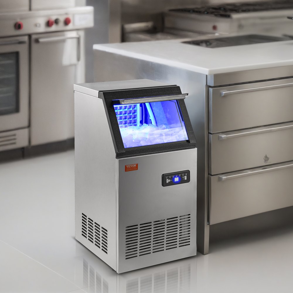 Máquina de hielo comercial VEVOR en una cocina moderna con electrodomésticos de acero inoxidable e iluminación LED azul.