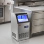 Máquina de hielo comercial VEVOR en una cocina moderna con electrodomésticos de acero inoxidable e iluminación LED azul.