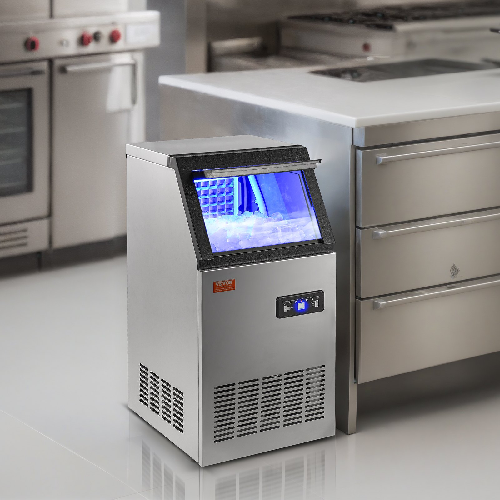 Máquina de hielo comercial VEVOR en una cocina moderna con electrodomésticos de acero inoxidable e iluminación LED azul.
