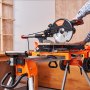 Soporte para sierra ingletadora VEVOR naranja y negro con sierra acoplada en un entorno de taller de madera.