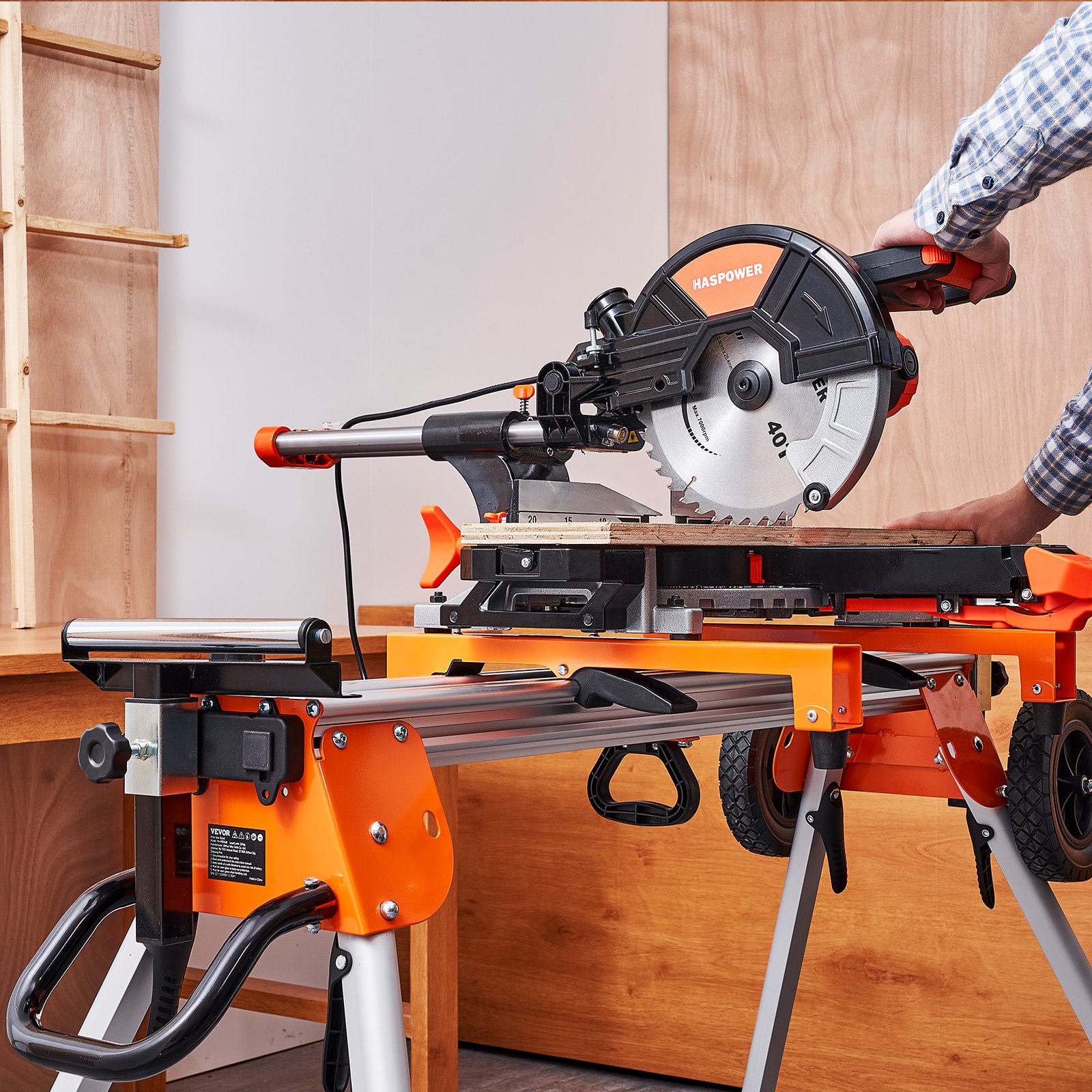 Soporte para sierra ingletadora VEVOR naranja y negro con sierra acoplada en un entorno de taller de madera.