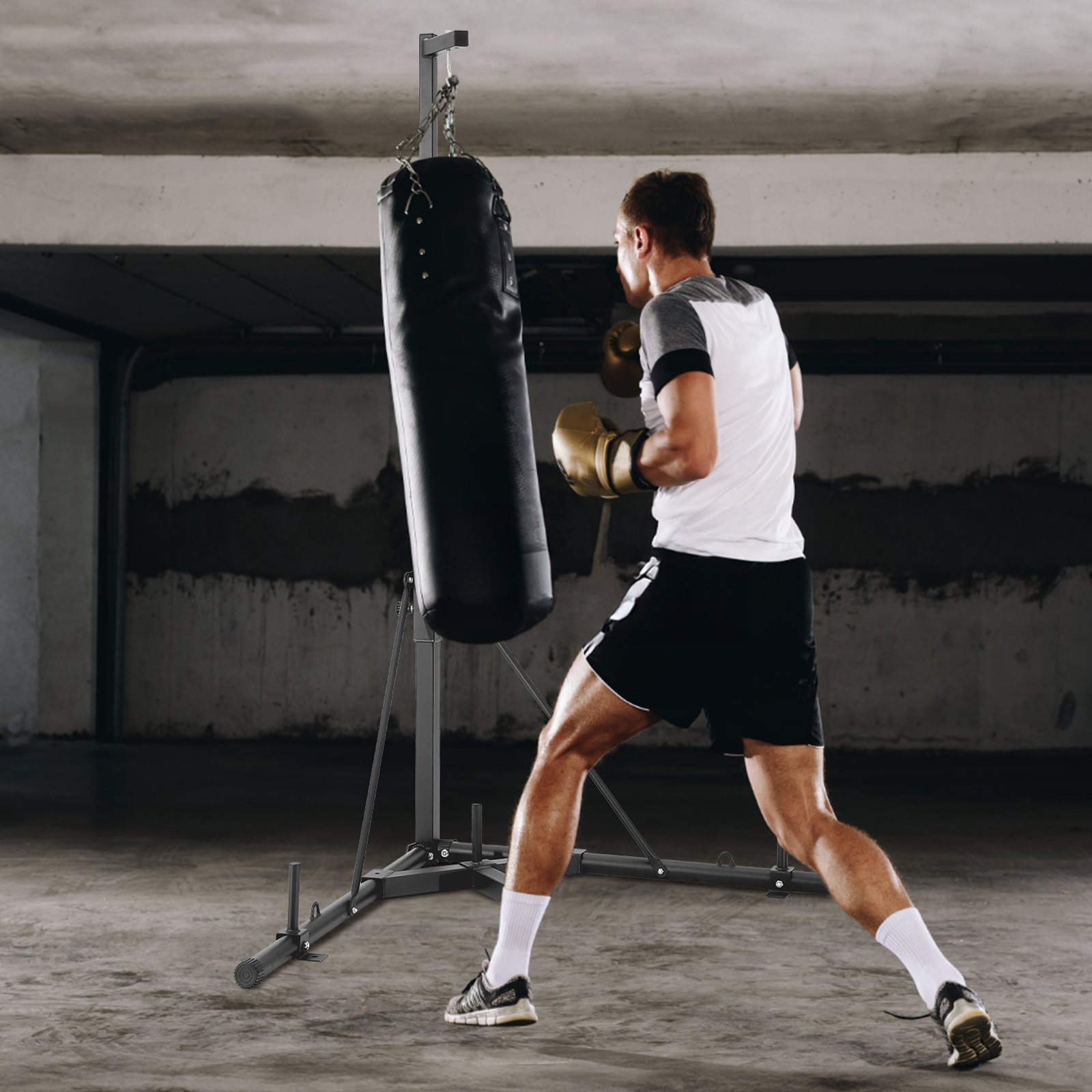Hombre boxeando con guantes en el stand de sacos de boxeo de VEVOR en un gimnasio subterráneo de hormigón.