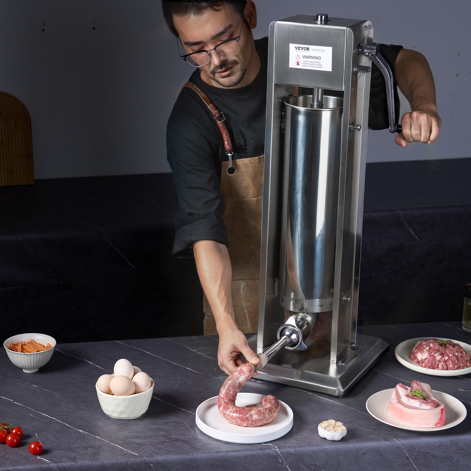Hombre operando una embutidora de salchichas VEVOR, llenando la tripa de salchicha con carne, rodeado de ingredientes.