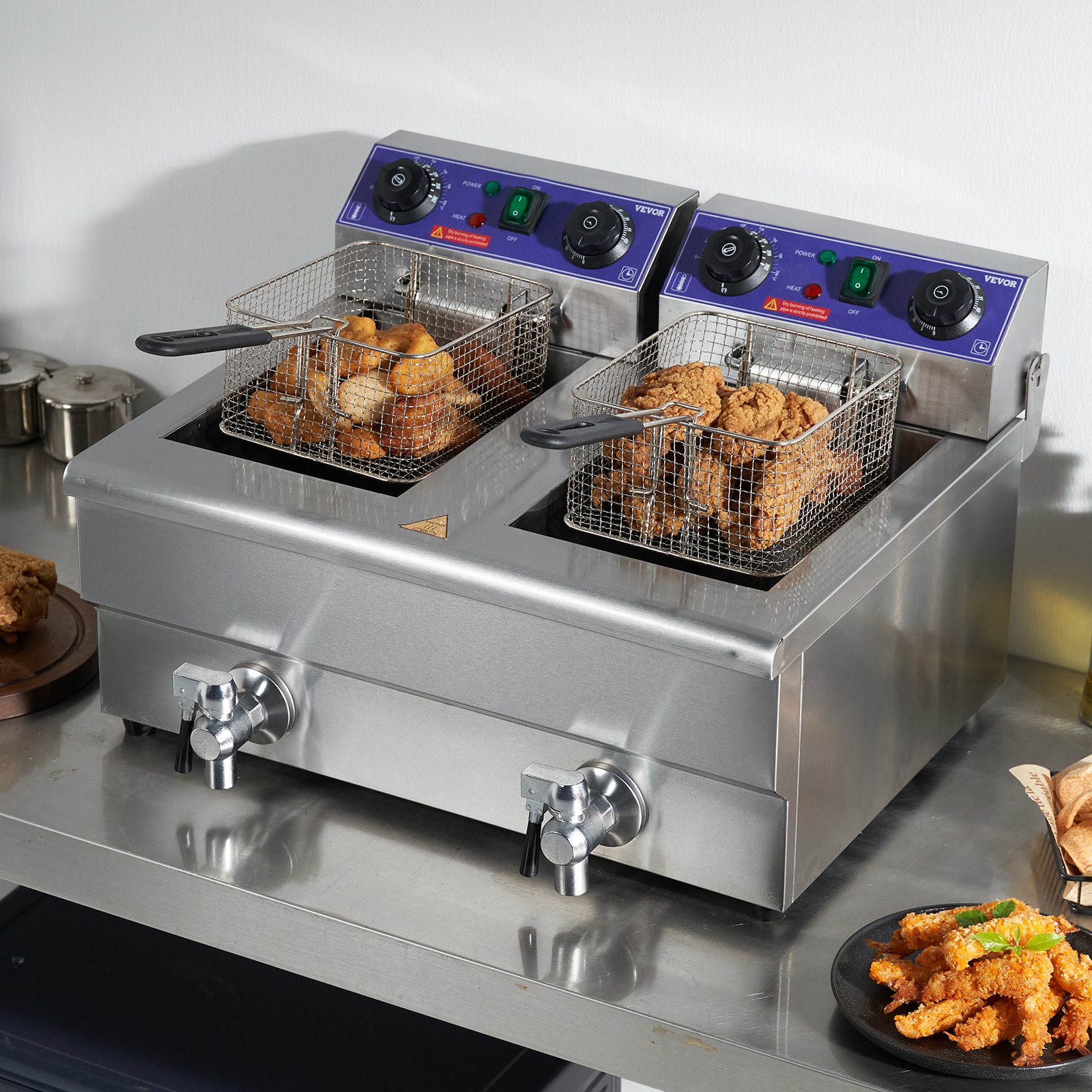 Freidora eléctrica VEVOR con cestas dobles para freír alitas de pollo sobre una encimera de acero inoxidable.