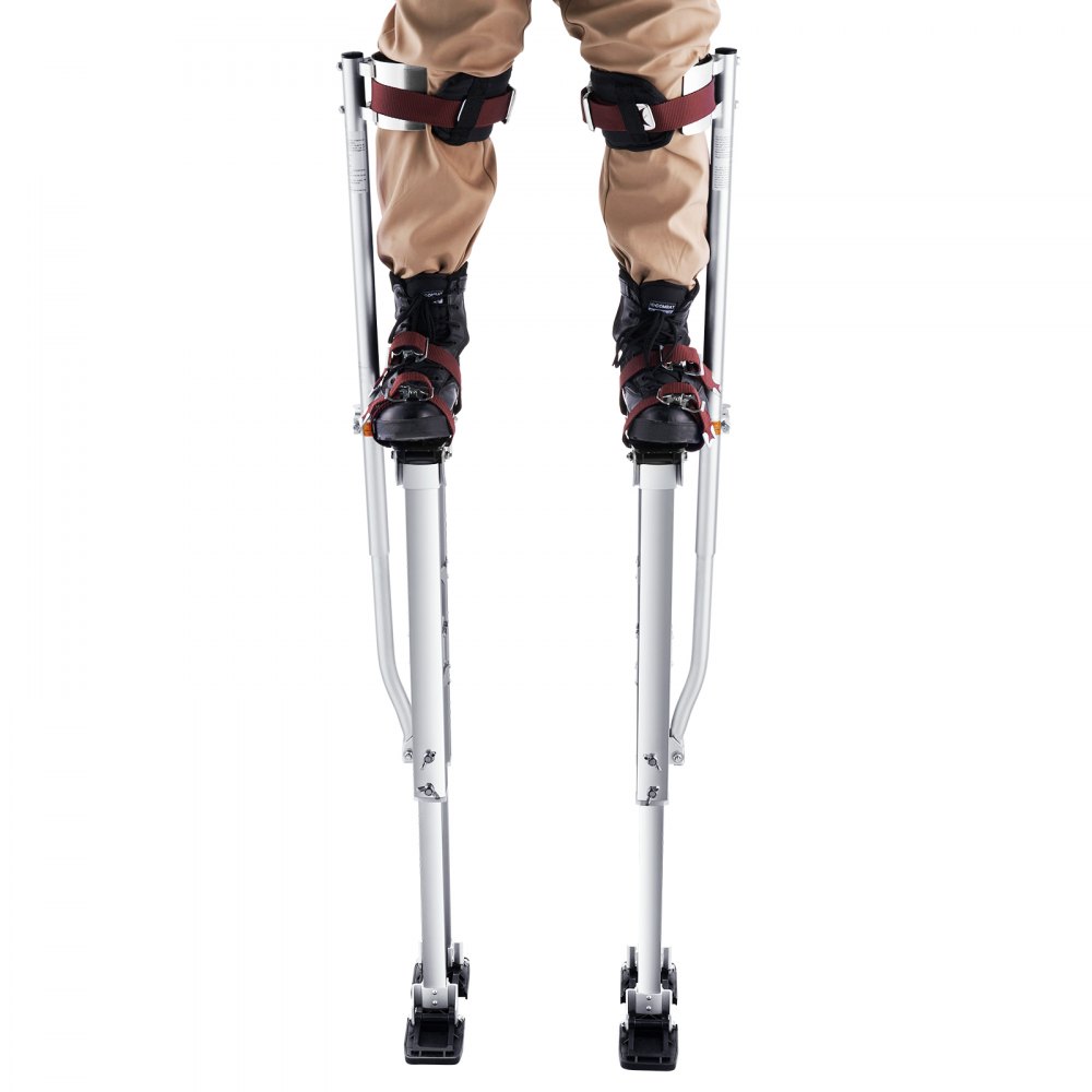 una persona que lleva pantalones beige y zancos de yeso VEVOR con botas negras y correas rojas.