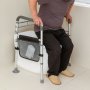 Persona mayor que utiliza el pasamanos de seguridad para inodoro VEVOR para recibir ayuda, con un organizador de malla que sostiene el pañuelo, en un entorno de baño.