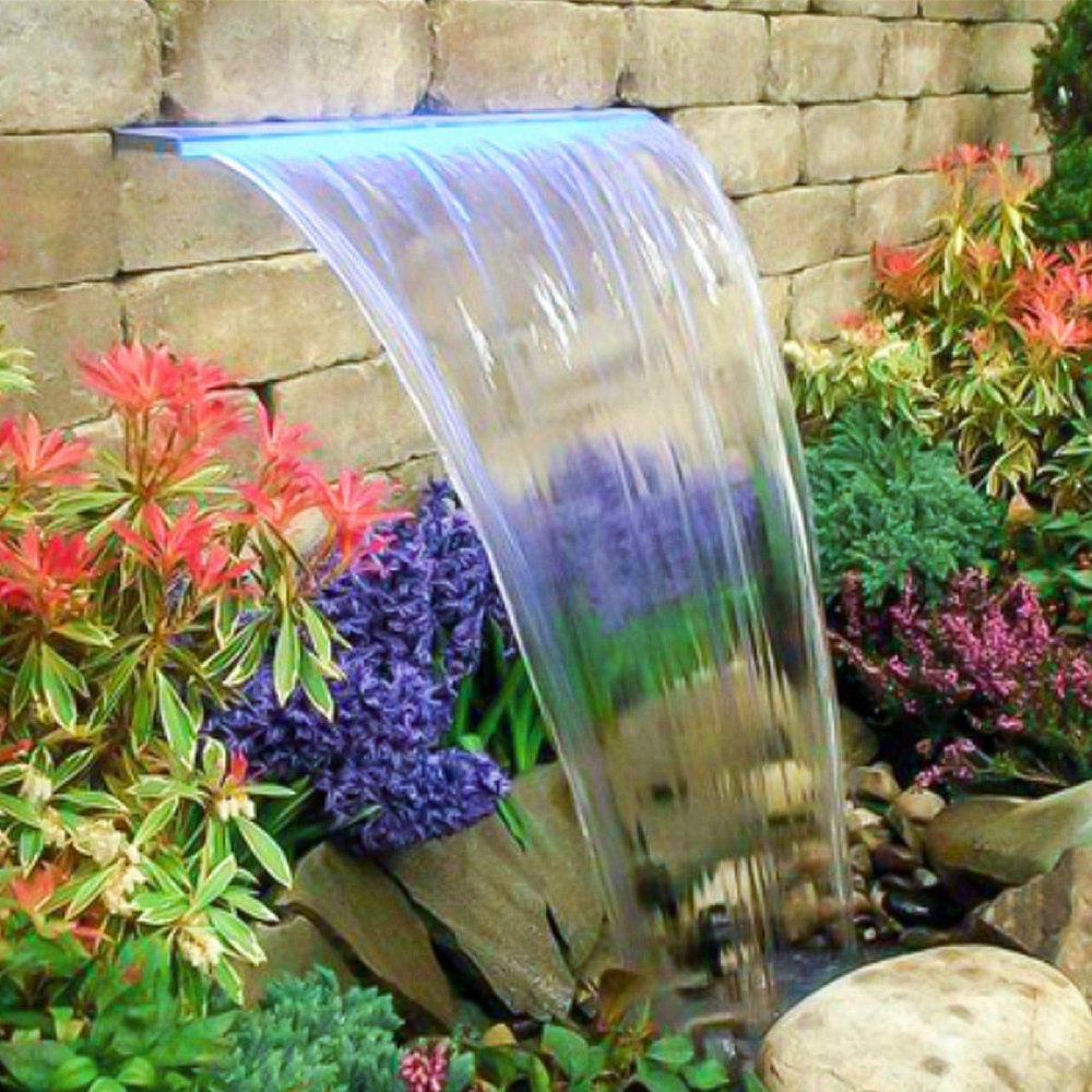 Aliviadero de fuente VEVOR con agua en cascada en medio de coloridas flores de jardín y un fondo de piedra.