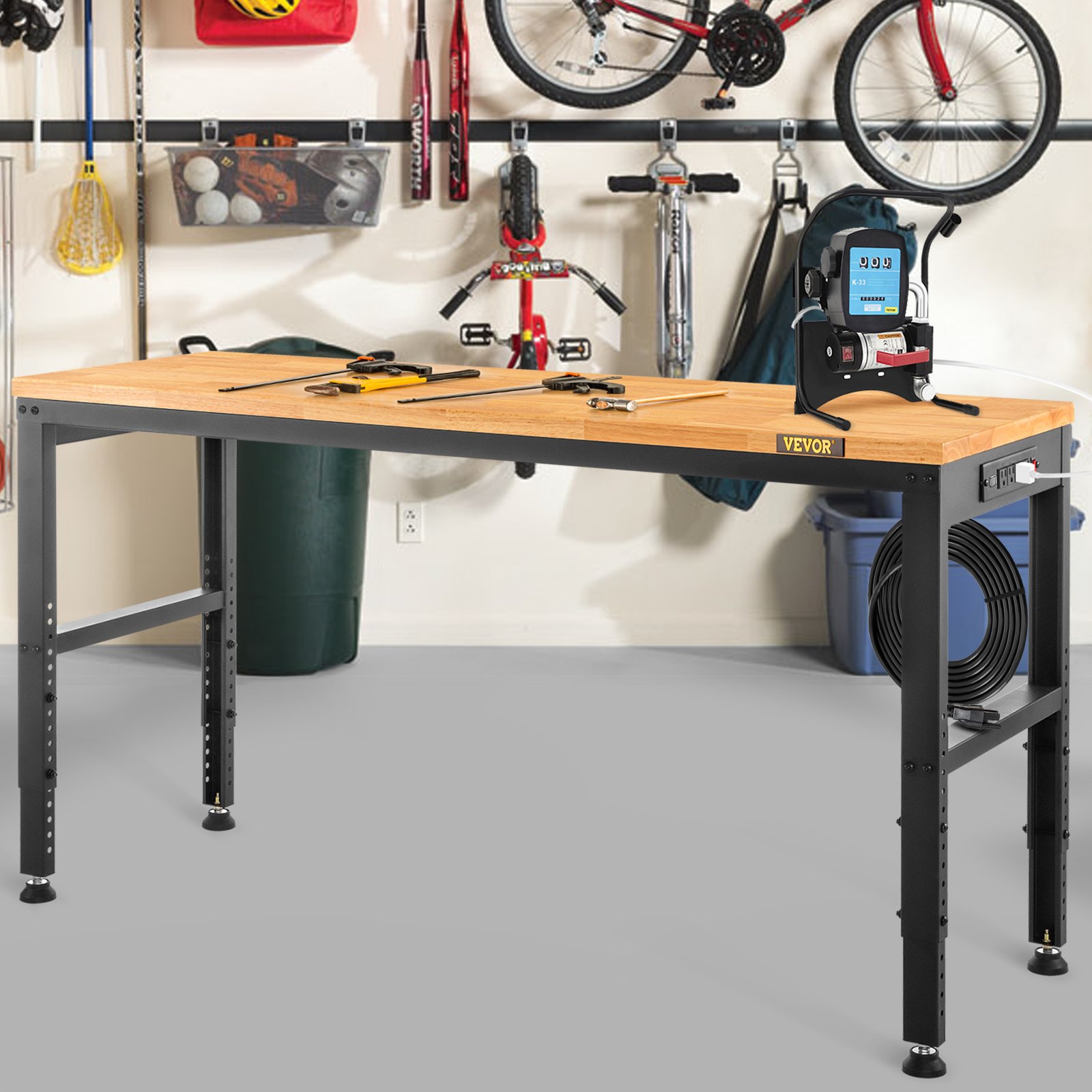 Banco de trabajo ajustable VEVOR en un garaje con herramientas en la superficie, bicicletas y equipo deportivo en el fondo.