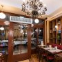 Cortina de aire interior VEVOR instalada sobre la puerta de un restaurante, con una elegante lámpara de araña y mesas de comedor cerca.