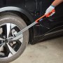 Llave dinamométrica digital VEVOR que aprieta las tuercas de una rueda de automóvil con una mano enguantada.