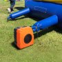 Soplador inflable VEVOR naranja conectado a un inflable azul en el césped.