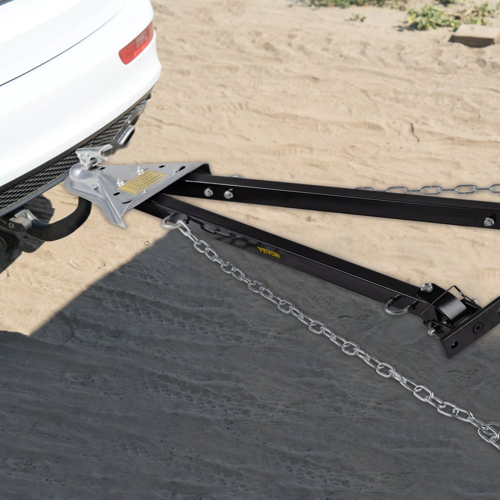 Barra de remolque VEVOR unida a un vehículo blanco, mostrada con cadenas de metal sobre suelo de tierra.