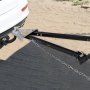 Barra de remolque VEVOR unida a un vehículo blanco, mostrada con cadenas de metal sobre suelo de tierra.