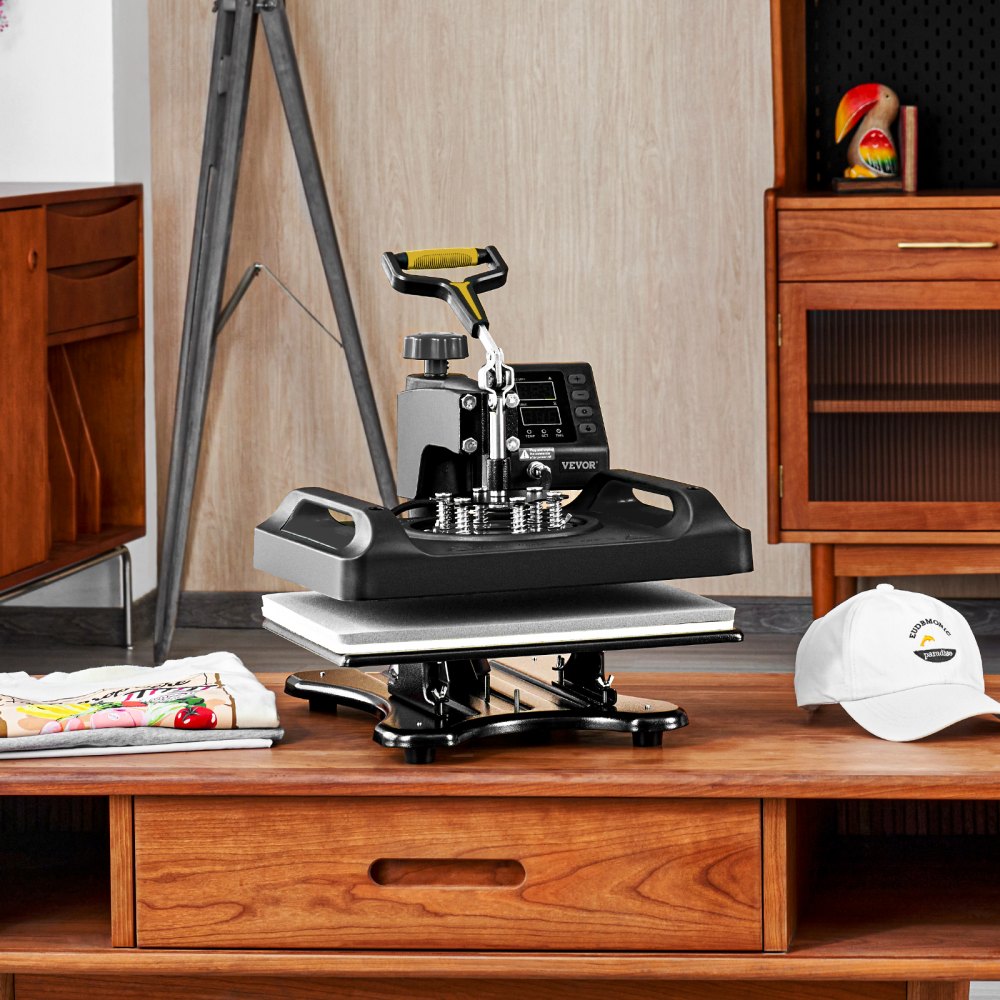 Máquina de prensado térmico VEVOR sobre una mesa de madera con una camiseta y un sombrero personalizados cerca.