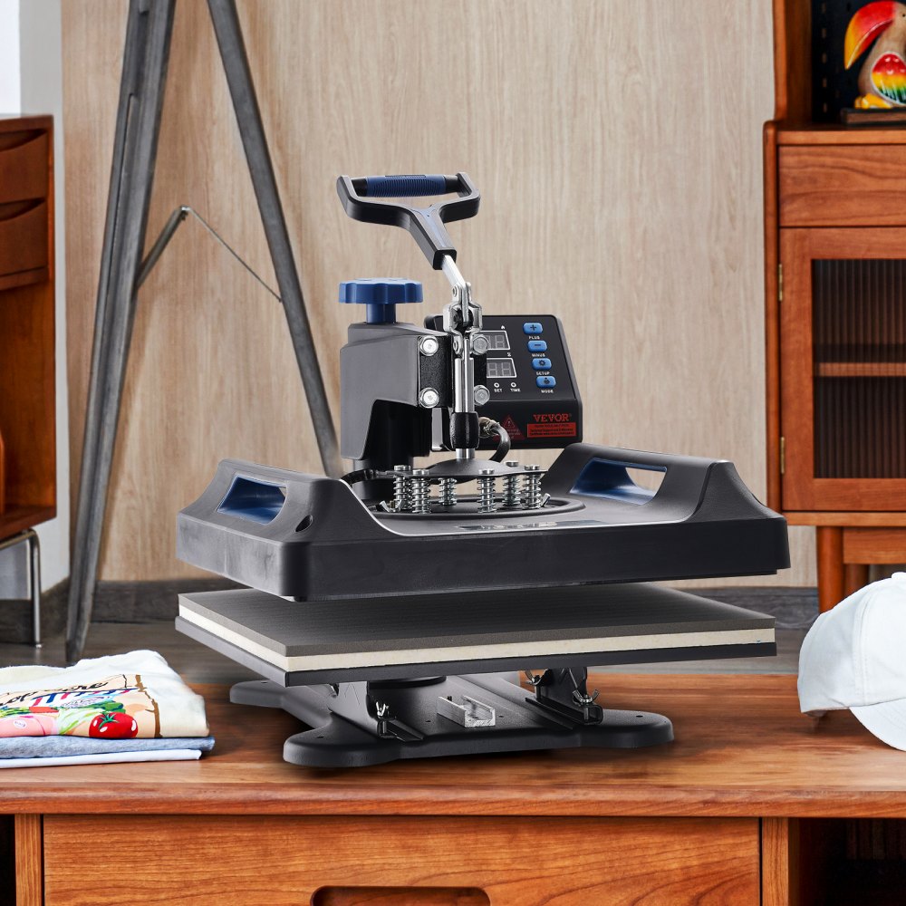 Prensa térmica VEVOR sobre una mesa de madera en un entorno doméstico con una toalla y una camisa cerca.