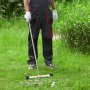 Persona que utiliza la barredora magnética VEVOR para recoger residuos metálicos del césped verde.