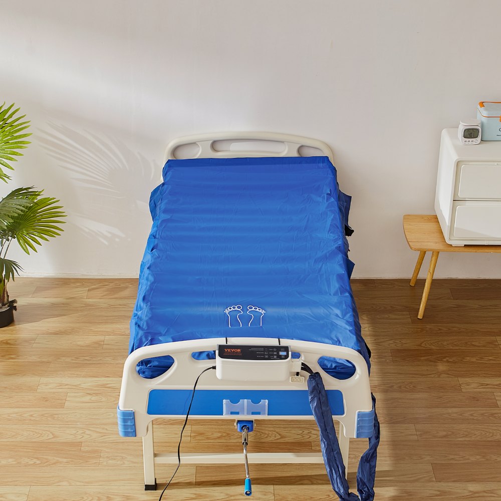 Colchón de presión de aire VEVOR sobre una cama de hospital con unidad de control, rodeado de una decoración clara y suelo de madera.